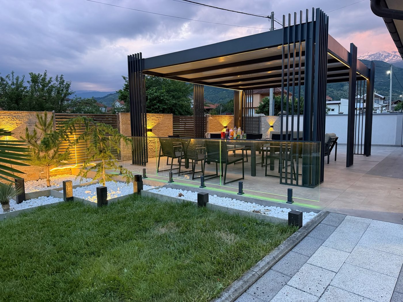 Terrasse mit moderner Aluminium-Pergola und warmer LED-Abendbeleuchtung